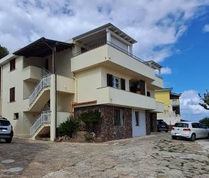 a building with cars parked in front of it at B&B L'alba Nel Golfo in Castelsardo