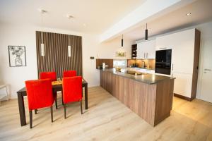a kitchen with a wooden table and red chairs at VARIO-HAUS Residence in Theresienfeld