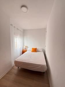 a white bedroom with a bed with an orange pillow at Apartamento céntrico, planta baja, zona muy tranquila con fácil aparcamiento in Andújar