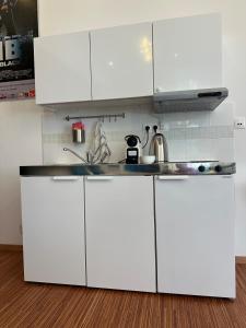 a white kitchen with white cabinets and a sink at PostersApt3-Cozy Cinema Vibes in Vienna