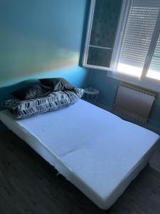 a white bed in a room with a window at Maison chaleureuse proche du circuit des 24h et autoroute in Écommoy