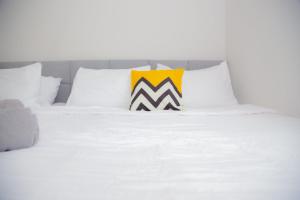 ein weißes Bett mit einem gelben und schwarzen Kissen darauf in der Unterkunft 5min walk to Tebrau ÆON Mall 1-5pax Free Netflix in Johor Bahru