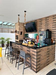 una cucina con un bancone con sedie attorno di Excelente casa de praia em Paripueira 5 min do mar a Paripueira