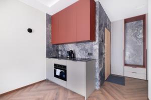 a kitchen with white counters and red cabinets at Sodų Vilos in Kaunas