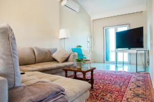 a living room with a couch and a flat screen tv at VILLA FAROS Angelochori in Angelochórion