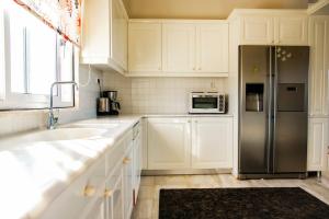 a kitchen with white cabinets and a stainless steel refrigerator at VILLA FAROS Angelochori in Angelochórion