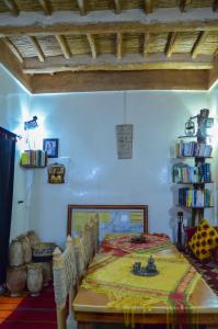 Habitación con mesa con sillas y estante para libros. en Kasbah Tussna, en Boumalne