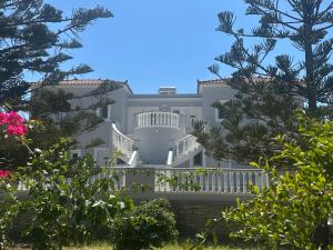 un gran edificio blanco con balcón y árboles en Villa Vourda, en Marathokampos