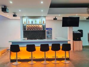 a bar with four stools in front of a counter at 7BR Luxury Resort with Pool and Bar in Sampong