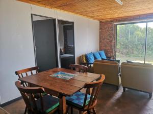 ein Esszimmer mit einem Holztisch und Stühlen in der Unterkunft Tokkelos - Beach front Bungalow in Witsand