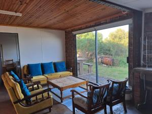 ein Wohnzimmer mit einer Couch und einem Tisch und Stühlen in der Unterkunft Tokkelos - Beach front Bungalow in Witsand