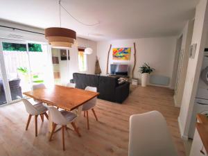 a dining room and living room with a table and chairs at Appartement 90 m2 avec parking terrasse balcons, proche du port et plages in Arcachon