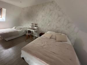 a bedroom with two beds and a white wall at Les gîtes de Joséphine proche Chambord in Courbouzon