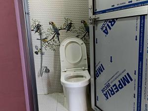a bathroom with a toilet with birds on the wall at Peace Home Homestay in Nagarkot