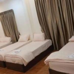 twee bedden in een kamer met gordijnen bij mulia homestay in Teluk Intan