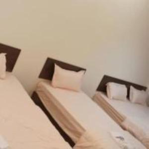two beds in a room with white sheets and pillows at mulia homestay in Teluk Intan