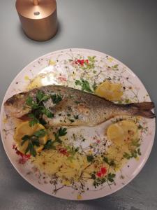 Un pescado en un plato con rodajas de limón. en Amarena Garden House, en Matera