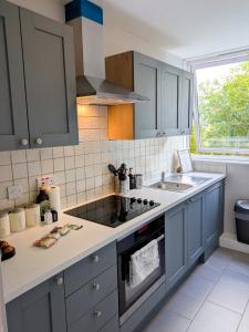 a kitchen with blue cabinets and a sink at NEW, Refurbished Modern & Spacious 1 Bed Flat Westfield Shepherd's Bush Free Wi-Fi Super King Bed in London