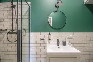 a green bathroom with a sink and a shower at Plac Matejki Apartments by Noah in Kraków +21 photos