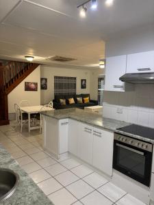 a large kitchen with white cabinets and a table at The Sandalwood Self-Catering Accommodation in Durban