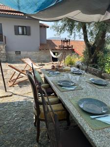 a table with chairs and plates and an umbrella at Casa Ermida in Pincães