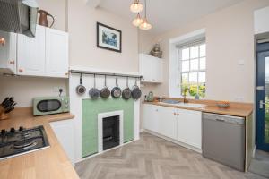 a kitchen with white cabinets and a green fireplace at Banrigh House in Stirling