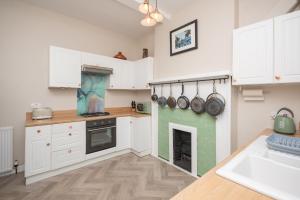 a kitchen with white cabinets and a fireplace at Banrigh House in Stirling +24 photos