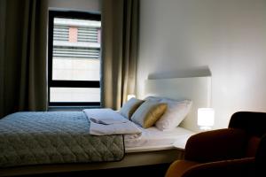 a bedroom with a bed with pillows and a window at Justinrent PALATIUM 13 in Legnica