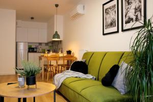 a green couch in a living room with plants at Justinrent PALATIUM 13 in Legnica