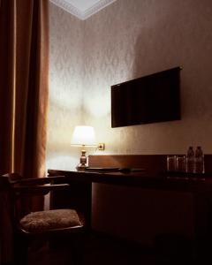 Habitación con escritorio con lámpara y TV. en Omar Khayyam Hotel, en Bukhara