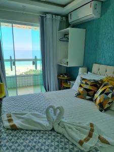 a bedroom with two swans towels on a bed at Hotel Aconchego da Vila A in Saquarema +72 photos