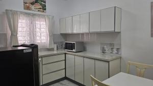 una cucina con mobili bianchi e un frigorifero nero di Anton White Villas Resort a Mamallapuram