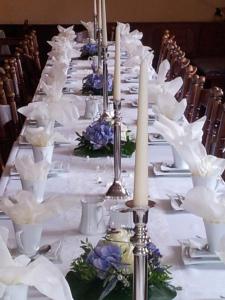 einen langen Tisch mit weißen Tellern und Kerzen darauf in der Unterkunft Landhotel zur guten Quelle in Eisenach