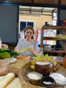 a girl sitting at a table with a bunch of bananas at Battambang Eco Stay &cooking class in Battambang