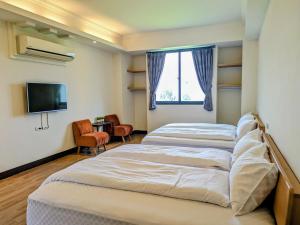 two beds in a room with a tv and a window at Yun Dan in Lugu