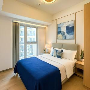 a bedroom with a large bed with a blue blanket at Luxury 1-Bedroom Apartment Across Okada Manila in Manila