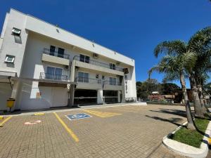 a large white building with a parking lot at Hotel Queijo & Cia in Capão Alto