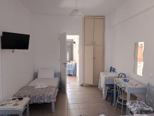 a room with two beds and a table and a tv at Anna Apartments in Agiokampos