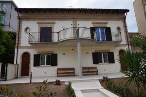 a white house with a balcony and two benches at Residenza Diomedea in Vasto