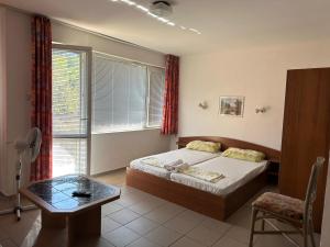 a bedroom with a bed and a table and a window at Guest House Villa Rose in Primorsko