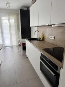 una cucina con armadi bianchi e un forno a piano cottura nero di Cloche d'or studio sleeps 2 a Lussemburgo
