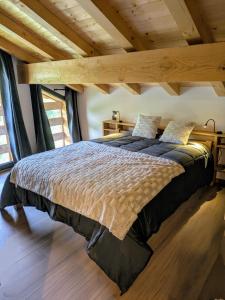 een groot bed in een kamer met een houten plafond bij Chalet La Tanière avec Sauna in Le Grand-Bornand
