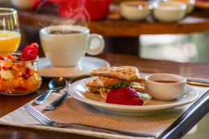 a plate of pancakes and strawberries and a cup of coffee at Coração da Terra Praia do Rosa in Praia do Rosa