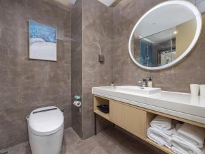 a bathroom with a toilet and a sink and a mirror at Kyriad Hotel in Tianjin