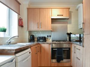 a kitchen with wooden cabinets and a stove top oven at Filey Central One - Uk31706 in Filey +8 photos