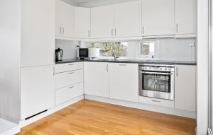 una cucina bianca con armadi bianchi e pavimenti in legno di 4 Bedroom Nice Home In Jørpeland a Jørpeland