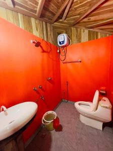 an orange bathroom with a toilet and a sink at Meghrani Eco Cottage in Māhmuam