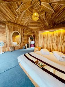 a bedroom with a large bed with a wooden ceiling at Meghrani Eco Cottage in Māhmuam