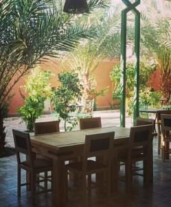 a wooden table and chairs in a room with palm trees at Riad safari camp in Merzouga