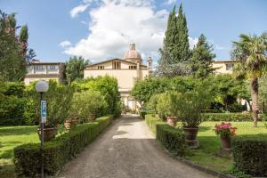 une allée menant à un bâtiment avec des arbres et des buissons dans l'établissement Casa Santo Nome di Gesu, à Florence